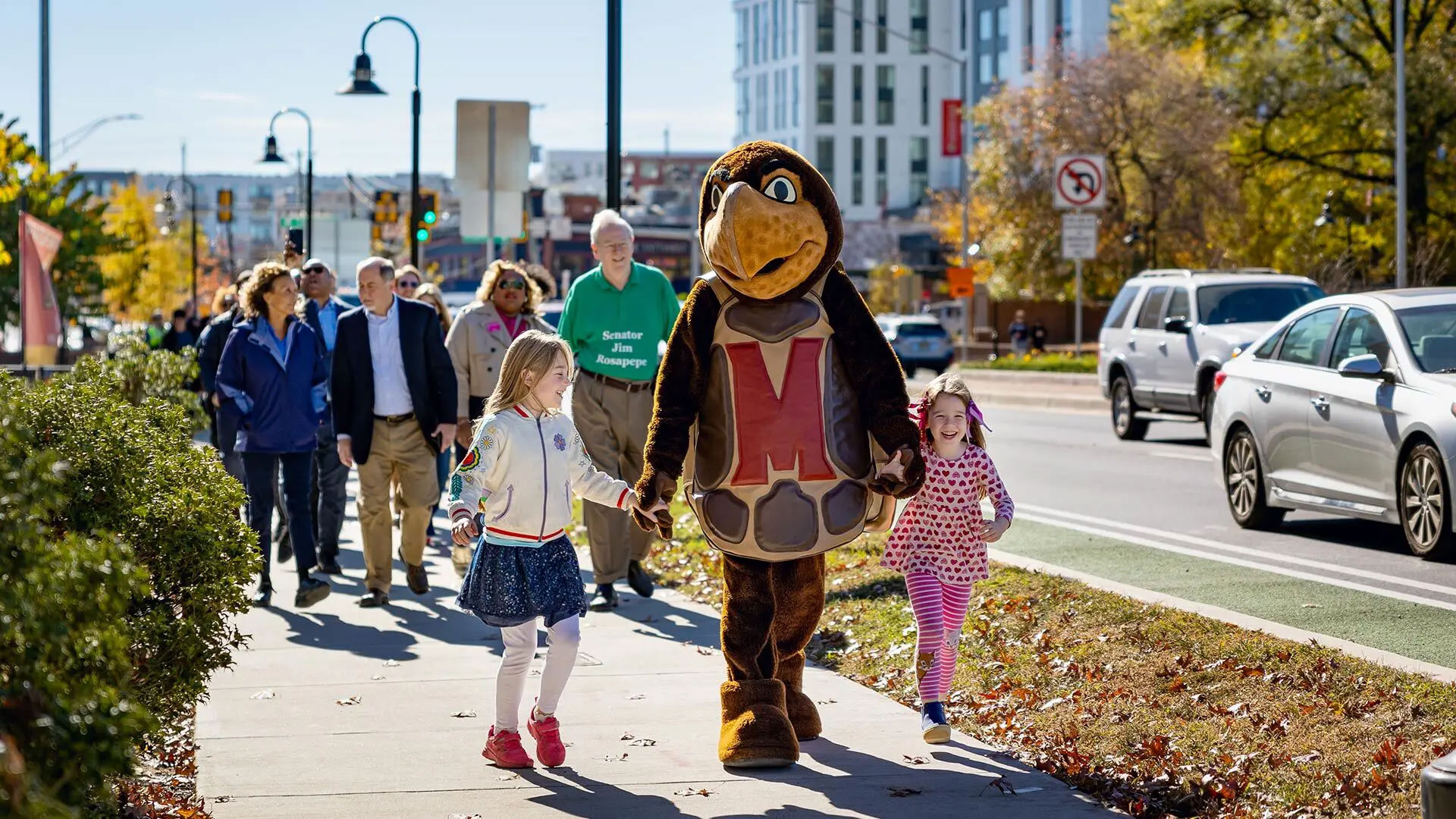 Testudo, Sybil Seabrook (left), and Rosie Seabrook (right) lead attendees of a ribbon-cutting ceremony down Baltimore Avenue on Saturday in celebration of the completion of a $56.9 million project to upgrade the street and boost safety along a 1.5-mile route. Photo by Riley N. Sims.