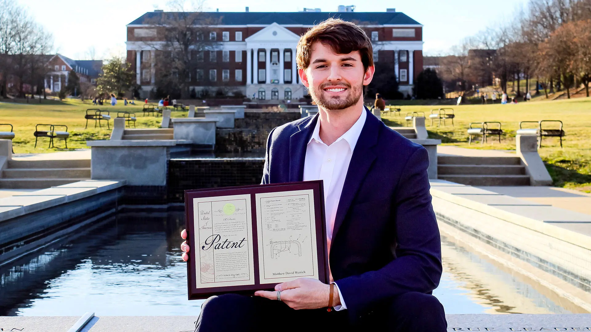 Matthew Weirich '25 poses with the patent for his invention to aid safe autonomous vehicle navigation on McKeldin Mall. Photo courtesy of Matthew Weirich.